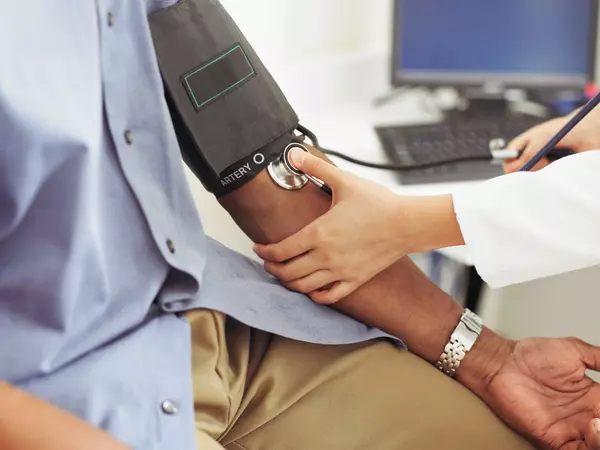 Female doctor taking patient's blood pressure in doctor's office.